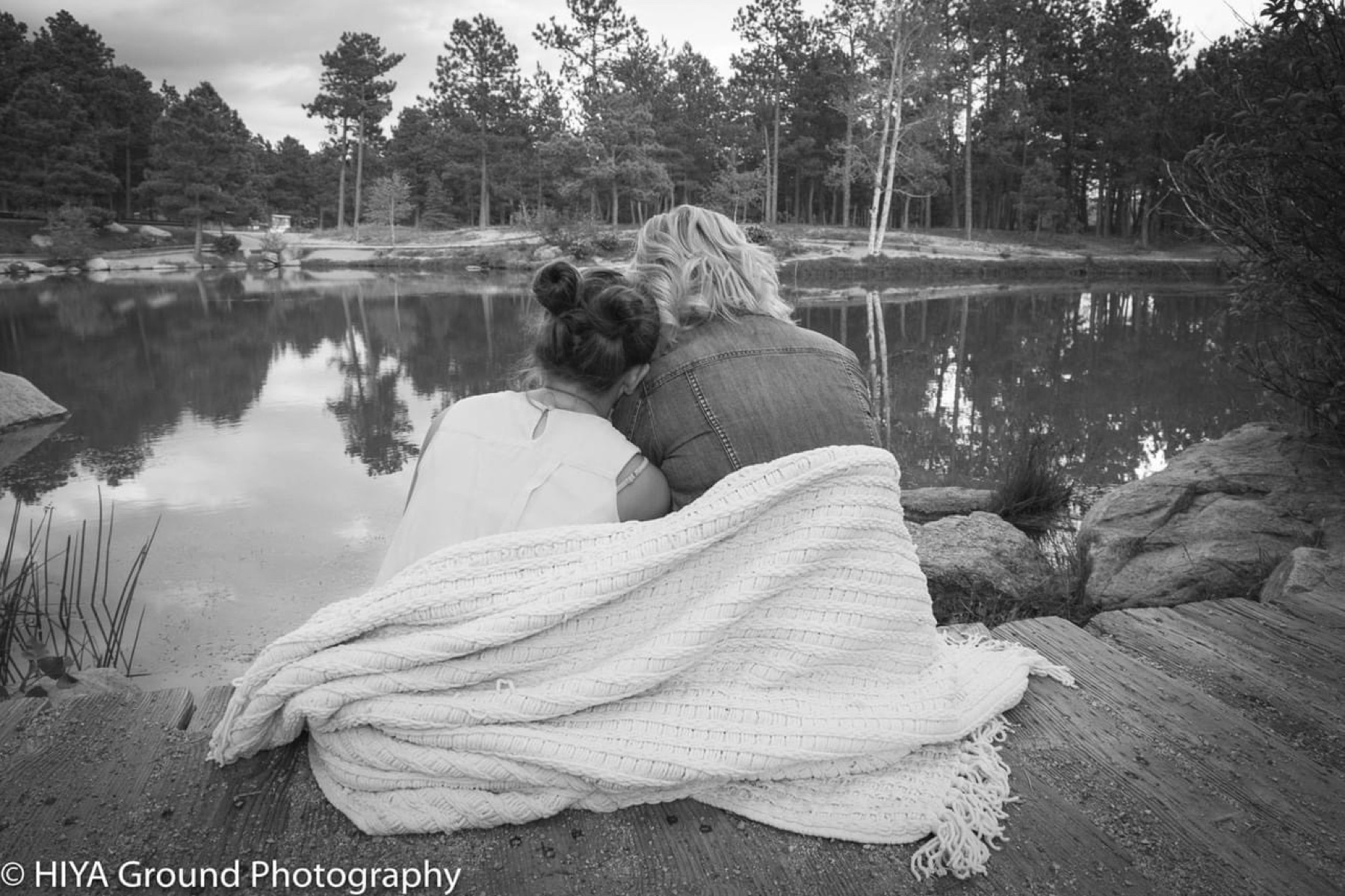Couple wrapped in a blanket by a lake