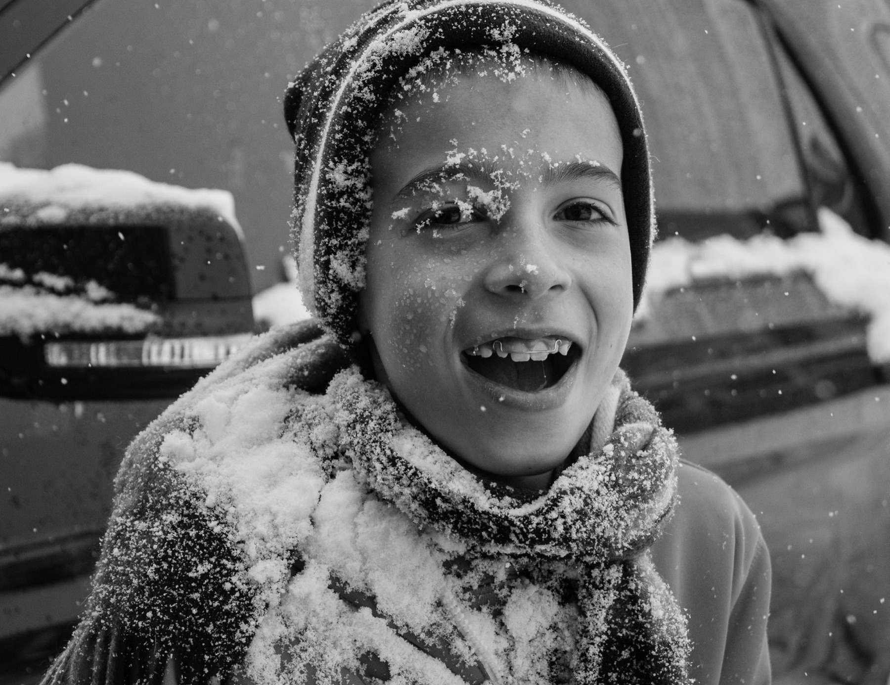 Kid laughing in falling snow, black and white