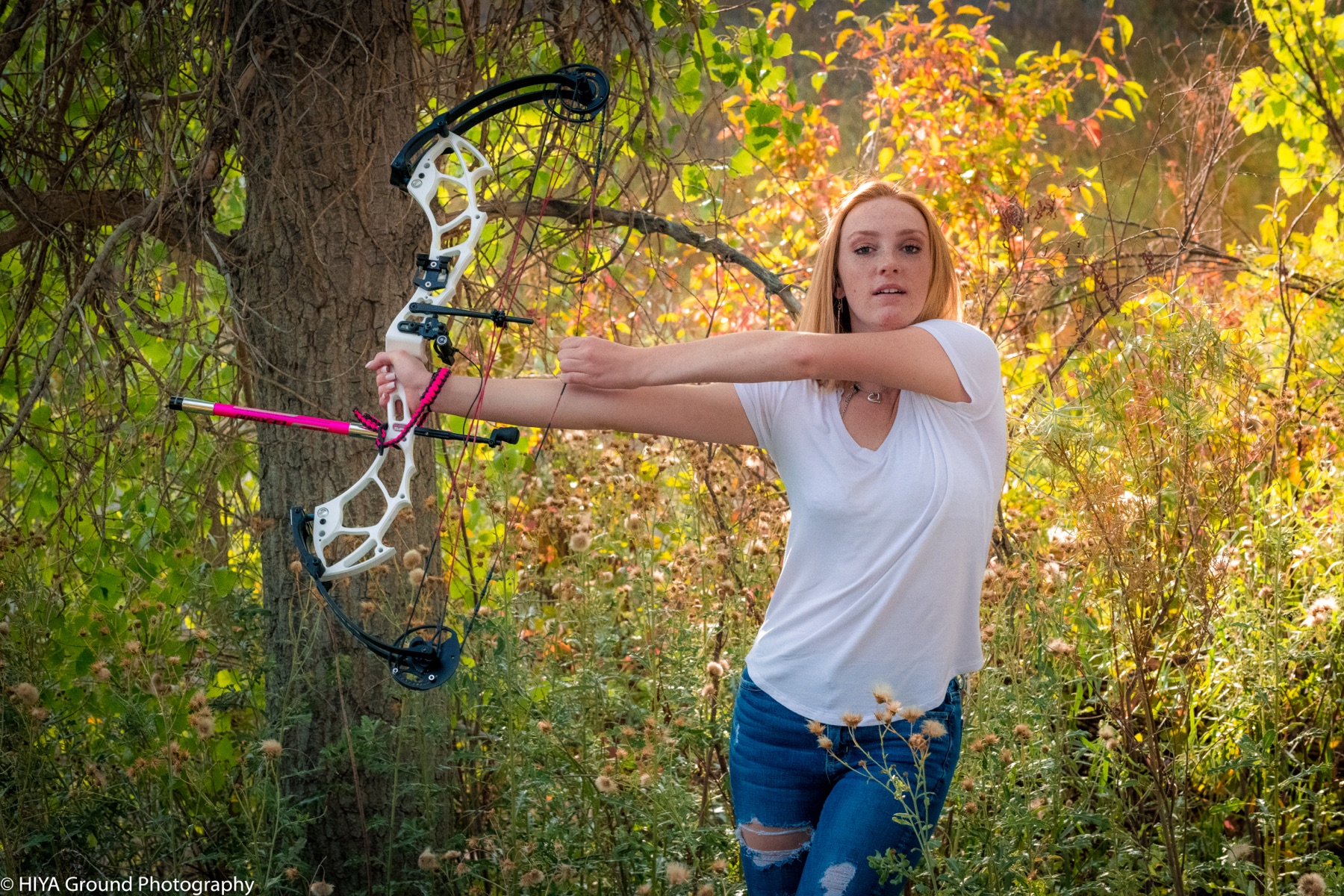Senior portrait drawing a compound bow